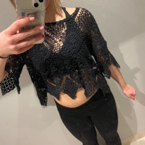 Svart spets topp  - Säljer en svart spets topp med ett unikt mönster och löst sittande passform. Toppen är kortärmad och har en croppad design som ger en trendig look. Perfekt för att lägga till en bohemisk touch till din outfit.