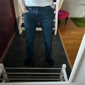 Blå jeans från Lee - Säljer ett par snygga blå jeans från Lee med en smal avsmalnande passform. De har en klassisk design med fem fickor och dragkedja. Perfekta för en stilren look. Det är storlek 32/32