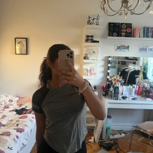 Grå och svart t-shirt - Säljer en stilren grå t-shirt med svarta ärmar. Perfekt för en avslappnad look. T-shirten har en rund hals och korta ärmar.