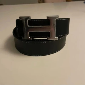 Svart H3rmes bälte - Snyggt svart H3rmes bälte med ett silverfärgat H-spänne. Perfekt för att ge en stilren touch till din outfit. Skick 6/10 || storlek 115. Priset kan diskuteras, Skriv vid frågor!