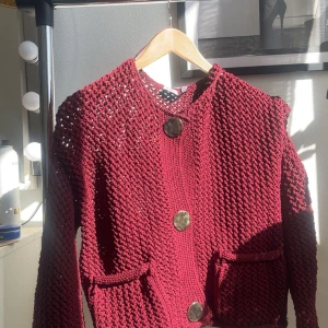 Vinröd stickad kofta från Zara - Säljer en snygg vinröd stickad kofta från Zara med stora dekorativa knappar. Koftan har en öppen stickad design och praktiska fickor framtill. Den kommer aldrig till användning därför säljer jag den. Kom privat för mer bilder❣️