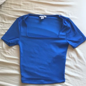 Blå topp från New yorker - Säljer en snygg blå topp från Amisu med fyrkantig urringning och korta ärmar. Perfekt för en stilren look. Från newyorker💞