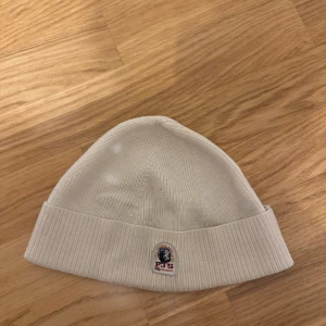 Off white ribbad mössa från Parajumpers - Snygg off white ribbad mössa från Parajumpers med broderad logga framtill. Perfekt för kyliga dagar och ger en stilren look. Tillverkad i mjukt material för extra komfort. Storlek S/M Nypris: 799 