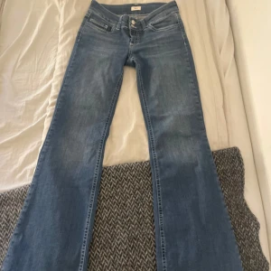 Blå bootcut jeans från Nelly  - Snygga blå bootcut jeans med klassisk femficksdesign och dekorativa sömmar på bakfickorna. Perfekta för en avslappnad stil med en touch av retro. De har en dragkedja och knapp framtill.