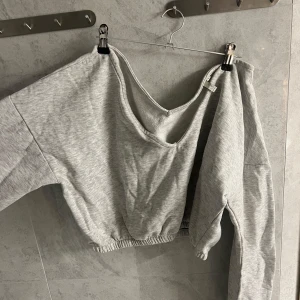 Grå croppad sweatshirt - Säljer en grå croppad sweatshirt med långa ärmar och elastisk nederkant. Perfekt för en avslappnad stil. Passar bra till jeans eller leggings.