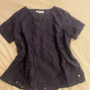 Mörkblå spetsblus - Säljer en elegant mörkblå spetsblus. Blusen har korta ärmar och en v-ringad halslinje. Säljer den då den aldrig kommer till användning. 💙Liten i storleken skulle säga M!