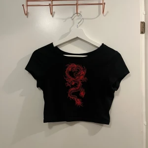 Svart croppad topp med röd drake - Snygg svart croppad topp med en cool röd drake på framsidan. .