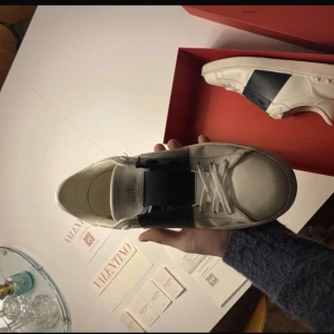 Valentino Garavani sneakers - Snygga vita Valentino Garavani sneakers med en bred mörkblå rem över ovansidan. Skorna har en stilren design. Allt som finns på bilderna får man med pris är går att diskutera passar även 43