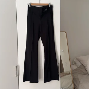 Svarta kostymbyxor med bootcut - Snygga svarta kostymbyxor med bootcut-stil. De har en normal hög midja och en dragkedja framtill. Perfekta för en stilren look. Från gina tricot i storlek xs