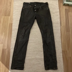 Levi's 501 svarta jeans W28 L32 - Svarta Levi's 501 jeans med klassisk rak passform och knappgylf. Jeansen har fem fickor, tydlig Levi's-lapp bak och röd etikett på bakfickan. Tillverkade i slitstarkt denimtyg, perfekta för en clean och tidlös look.