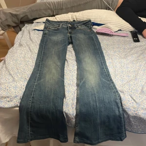 Blå bootcut jeans från Monki 24/32 - Säljer ett par blå bootcut jeans från Monki i storlek 24/32. Jeansen har klassisk femficksdesign, snygga slitningar och en ljus tvätt. De är tillverkade i jeansmaterial och har en normal passform upptill med utsvängda ben.