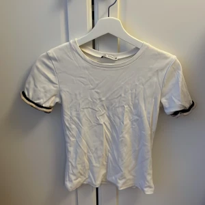 Vit t-shirt zara - Vit t-shirt från Zara i storlek S. Modellen har korta ärmar med svart & guldig detalj🩷