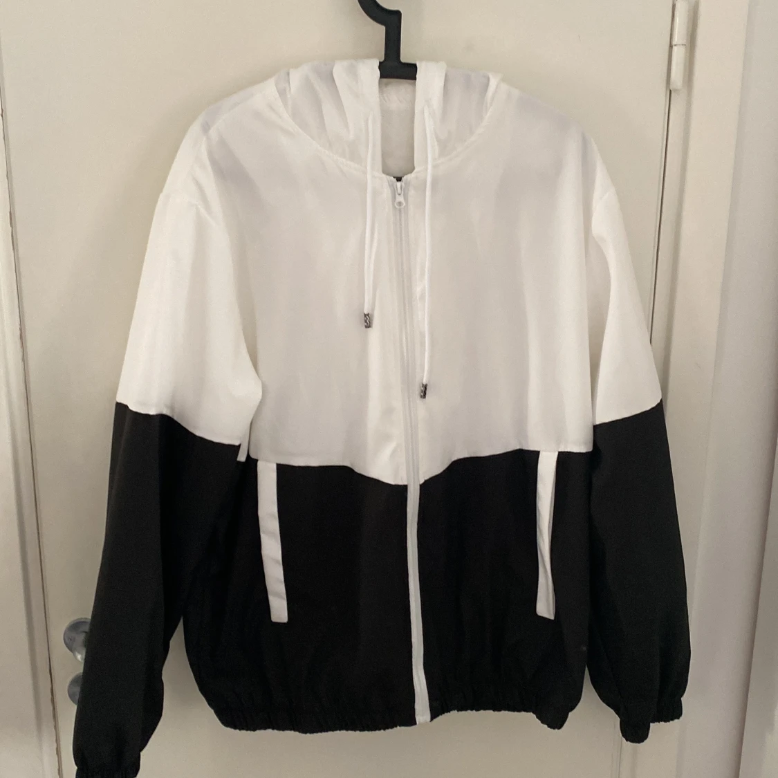 Svartvit vindjacka med huva