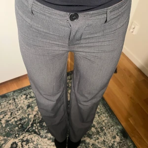 Grå kostymbyxor med wide fit - Snygga grå kostymbyxor med klassisk passform och vida ben. Byxorna har hög midja, hällor för bälte och stängs med knapp och dragkedja. Perfekta för en clean och stilren look samt att de är så sköna!🫶🏻
