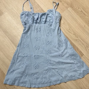 Ljusblå kort klänning från ASOS DESIGN - Supersöt ljusblå klänning från ASOS DESIGN med broderade blommor och tunna axelband. Modellen är kort och har en lätt A-linjeformad siluett. Perfekt för varma dagar och har en feminin touch med de små broderade detaljerna.