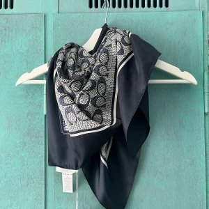 Mörkblå silkescarf från Coach - Snygg fyrkantig scarf från Coach i mörkblått och vitt med klassiskt logomönster. Tillverkad i 100% silke. Helt ny, med prislapp. 