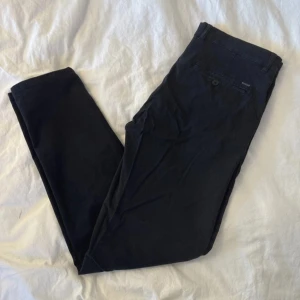 Mörkblå chinos från Esprit - Snygga mörkblå chinos från Esprit med klassisk rak passform. Byxorna har sidfickor, bälteshällor och en bakficka med knapp. Perfekta för en clean och stilren look. Tillverkade i mjuk bomull för skön känsla hela dagen.