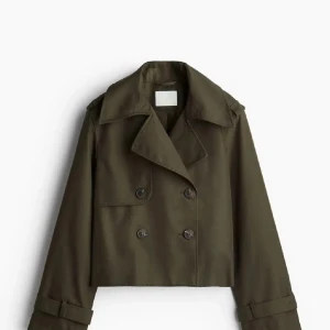 Olivgrön croppad trenchcoat - Snygg croppad trenchcoat i olivgrönt med dubbelknäppning och bred krage. Jackan har långa ärmar med spänndetaljer vid handlederna och en loose passform. Perfekt för dig som vill ha en trendig och stilren look till höst och vår. Saknar dock ett band vid ena armen! Funkar absolut att ha helt utan band, populär och helt slutsåld!!!