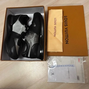 Louis Vuitton svarta sneakers stl 43 - Exklusiva Louis Vuitton sneakers i svart och silver med ikoniskt LV-monogram. Skorna har snörning, robust sula och är tillverkade i skinn och syntet. Snygg kontrast mellan svart och silver, samt tydliga LV-detaljer på både ovandel och sula. Perfekta för dig som vill sticka ut.