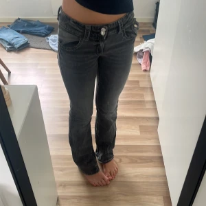 Svarta bootcut jeans Gina Tricot - Säljer ett par svarta bootcut jeans från Gina Tricot i storlek 170. Jeansen har låg midja, klassiska fem fickor och dubbla knappar framtill. Snygg tvättad look och stretchigt material som sitter tajt upptill och släpper vid benslutet.