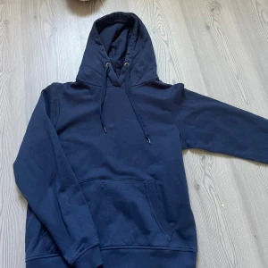 Mörkblå hoodie med huva och ficka - Säljer en enkel och stilren mörkblå hoodie med stor huva och snörning. Tröjan har en klassisk magficka och långa ärmar med ribbade muddar. Knappt använd🌸