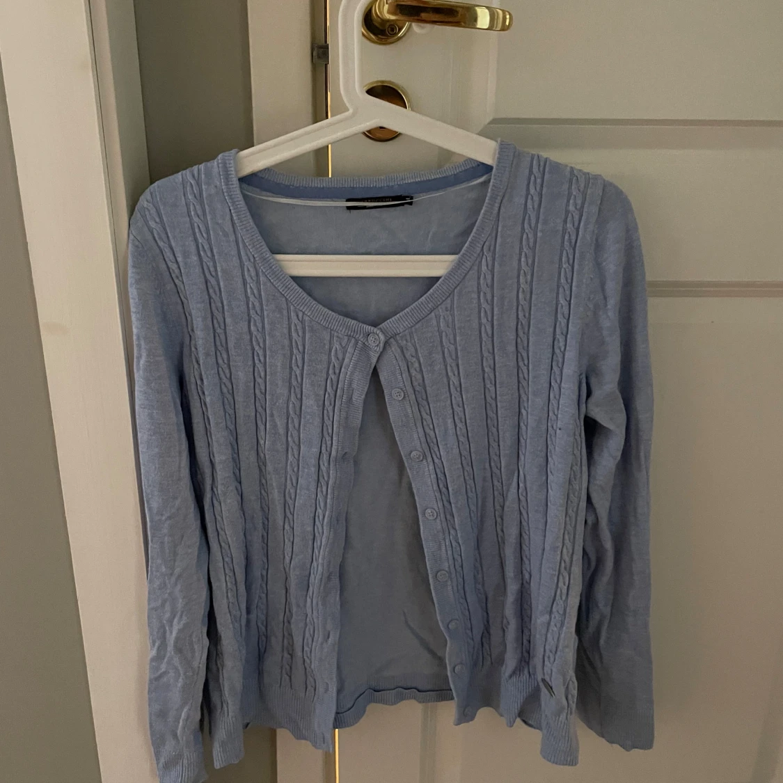 Ljusblå kofta med kabelstickning