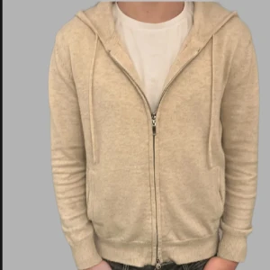 Beige hoodie från Braidbelt UF - Säljer en stilren beige hoodie från Braidbelt UF. Den har en dragkedja framtill och en klassisk huva med dragskedja. Perfekt för en avslappnad look. Passar bra till jeans eller joggers. Nypris 750kr vårat pris 350kr