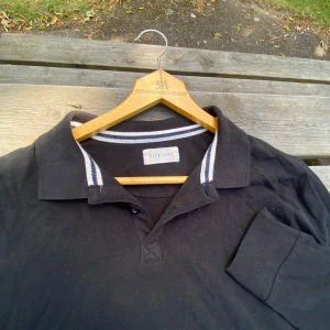 Svart långärmad pikétröja Pier One - Svart långärmad pikétröja från Pier One med klassisk krage och vita ränder på kragen. Hör av dig vid frågor!