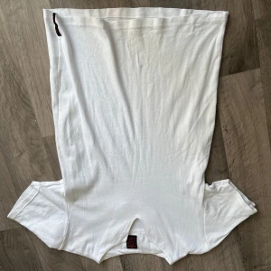 Vit t-shirt från UZ M - Vit t-shirt från UZ M med klassisk rund hals och korta ärmar. Tillverkad i mjuk bomull som känns skön mot huden. Enkel och clean design utan mönster eller tryck, perfekt för en chill och avslappnad stil.