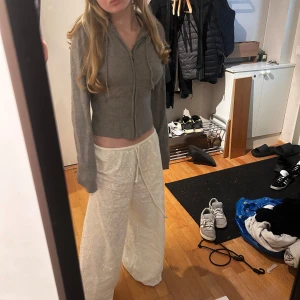 Grå stickad  jacka med huva från Gina  - Grå stickad  jacka med dragkedja framtill och huva. Modellen är croppad och har långa ärmar samt ribbad midja och ärmslut. Knappt använd då den sitter lite stort på mig. Storlek M 