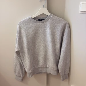 Grå sweatshirt från FB Sister XS - En basic ljusgrå sweatshirt från FB Sister i storlek XS. Tröjan har rund halsringning, ribbade muddar vid ärmslut och nederkant samt en loose passform. Perfekt för chill dagar eller när du vill ha en enkel och stilren look.