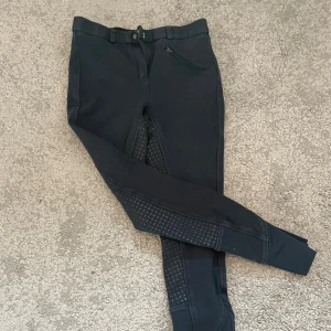 Mörk blåa CRW ridbyxor  - Säljer ett par mörk blåa ridbyxor från CRW i storlek 160. De är i ett något tjockare material. Byxorna har helskodd silikon för extra grepp, bälteshällor och en dragkedjeficka framtill. Snygg och sportig look, perfekta för ridning och träning.