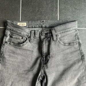Grå Levi's 511  - Säljer ett par grå Levi's 511 jeans med klassisk femficksdesign och smal passform. Jeansen har en snygg, neutral grå tvätt och är tillverkade i mjukt bomullsmaterial med lite stretch. Perfekta för dig som gillar en clean och stilren look.