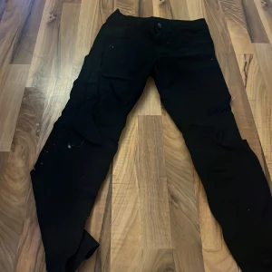 Svarta cargobyxor från Kappahl lite hårig  - Svarta cargobyxor från Kappahl i storlek 152. Byxorna har flera fickor på sidorna och klassisk cargomodell. Perfekta för en avslappnad och cool stil. Materialet känns slitstarkt och passar till många olika outfits.