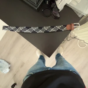 Onewear bälte! - Snyggt mörkblått bälte med vita och gråa geometriska mönster. Spännet är i silverfärgad metall och bältet har detaljer i brunt skinn vid spännet. Perfekt accessoar för att lyfta din outfit.