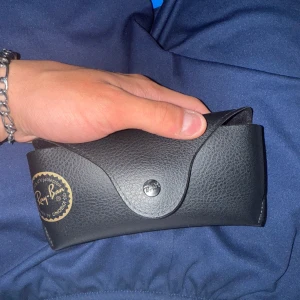 Ray-Ban bruna solglasögon - Snygga Ray-Ban solglasögon med breda, bruna bågar och mörka linser. Modellen har en klassisk, lite fyrkantig form och Ray-Ban-loggan på både lins och skalmar. Medföljer svart fodral i skinnimitation med tryckknapp och gul logga.