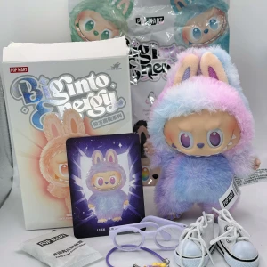 Äkta Pop Mart Labubu Luck med streckkod  - Jättegulliga lila Big Into Energy Luck från Pop Mart The Monsters  Hon är äkta med streckkod både på kartongen och på hennes egen etikett Du kan själv scanna koden på hennes lapp & verifiera henne på Pop Marts hemsida. Luck får med sig ett par snygga lila glasögon, en gullig lila kamera, ett par coola vita sneakers med snörning, sitt Luck kort och kartong & foliepåse Hon har vridbart huvud, fötter och böjbara armar Allt är som nytt i perfekt skick! Kartong & påse är dock öppnade