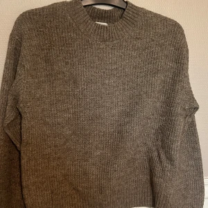 Brun stickad tröja från H&M - Mysig brun stickad tröja från H&M med rund halsringning och ribbade muddar. Perfekt för lager-på-lager och chill höst- eller vinterstil. Klassisk modell med lång ärm och relaxed fit.