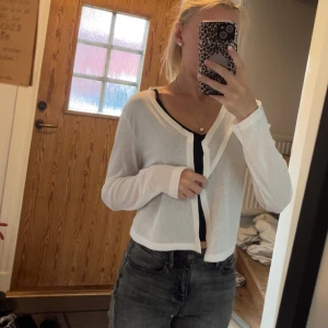 Vit tunn kofta - Säljer en tunn och luftig vit kofta. Koftan är långärmad, har en croppad passform och är perfekt att slänga över ett linne eller topp. Enkel och stilren design som passar till många outfits.