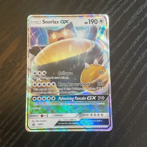 Snorlax GX - Snorlax GX är ett glittrande Pokémon-samlarobjekt med coola attacker som Collapse, Thunderous Snore och Pulverizing Pancake GX. Perfekt för dig som älskar Pokémon och vill boosta din samling med en kraftfull och unik kort! Samlarkort från 2016.
