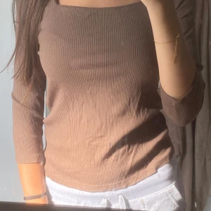 Ribbad brun topp från Object XS - Säljer en ribbad brun topp från Object i storlek XS. Toppen har en fyrkantig halsringning och långa ärmar, vilket ger en chill och modern vibe. Materialet är mjukt och stretchigt, perfekt för dig som gillar slim fit och enkel stil.