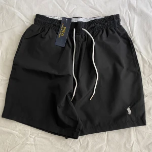 Polo Ralph Lauren Shorts  - Helt nya svarta shorts från Polo Ralph Lauren med vit snörning i midjan och klassisk logga broderad framtill. De har elastisk midja, sidofickor och en bakficka. Materialet är lätt och perfekt för varma dagar. Storlek M men passar mer för S. Priset kan diskuteras😊