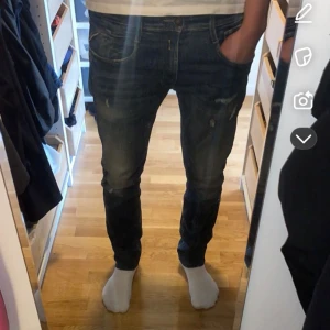 Blå Replay jeans med slitningar - Snygga blå jeans med slitningar och en klassisk femficksdesign. Perfekta för en avslappnad stil. Storlek W32/L34. Jeansen är använda Max 5 gånger och är i jätte bra skick. Nypris 800kr, personen på bilden är 187cm