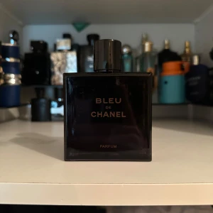 Bleu de Chanel Parfum 100ml - Säljer en exklusiv Bleu de Chanel Parfum i 100ml flaska. Flaskan är mörkblå, nästan svart, med stilren fyrkantig design och elegant svart kork med Chanel-logga. En ikonisk doft som utstrålar lyx och modernitet. Den har fortfarande minst 98ml kvar.