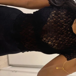 Svart spetsblus med kort ärm från newYorker  - Säljer en svart blus i spets med korta ärmar och rund hals. Blusen är genombruten och har en feminin, figurnära passform. Perfekt att styla med jeans eller kjol för en trendig look.