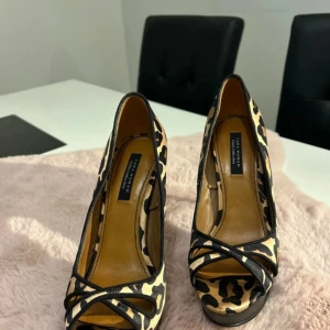 Leopardmönstrade pumps från Zara Woman - Snygga pumps från Zara Woman Cruise Collection med leopardmönster i beige och svart. Skorna har hög klack, öppen tå och plattform framtill. Materialet är syntet med läderimitation och svarta detaljer över tårna. Perfekta för dig som vill sticka ut.
