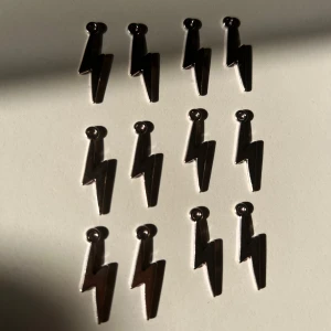 Blixtformade silvriga berlocker  - Säljer flera berlocker i form av blixtar i blankt silverfärgat material. De har en cool och edgy design som verkligen sticker ut. Perfekta för dig som vill ha en unik detalj till din stil. För 4kr styck.