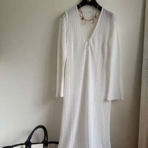 Vit lång spetsklänning med v-ringning - Säljer en vit långklänning med v-ringad hals och knapp framtill. Stl passar S-M. I perfekt skick 