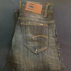 G-Star Raw 3301 jeans i mörkblå denim - Snygga G-Star Raw 3301 jeans i mörkblå tvättad denim med klassiska kontrastsömmar och femficksdesign. Märkespatch i läder baktill och diskret logga på fickan. Perfekta för dig som gillar en stilren och tidlös look. Pris kan diskuteras vid snabb affär 