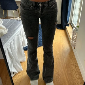 Mörkgrå bootcut jeans med slitningar - Säljer ett par mörkgrå bootcut jeans med snygga slitningar på låren. Jeansen har en tvättad look och klassisk femficksdesign. Längden är normal och midjan är low waist. Omsydda! Köpta utomlands för 500.